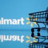Shopping trolley is seen in front of Walmart logo in this illustration
