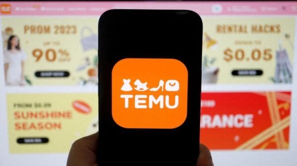 The logo of Temu, an e-commerce platform owned by PDD Holdings, is seen on a mobile phone displayed in front of its website, in this illustration picture taken April 26, 2023. REUTERS/Florence Lo/Illustration/File Photo