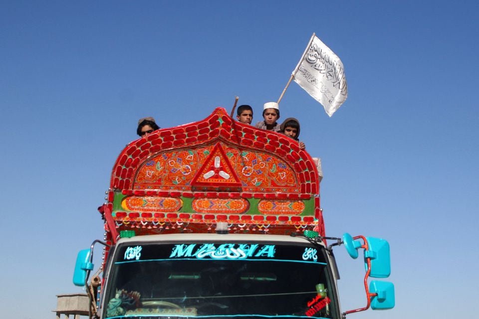 Afghan boys wave an Afghanistan flag as they board a truck while heading back with their family to Afghanistan from Pakistan, at the Chaman Border Crossing along the Pakistan-Afghanistan Border in Balochistan Province, in Chaman, Pakistan November 10, 2023. REUTERS/Naseer Ahmed/File Photo