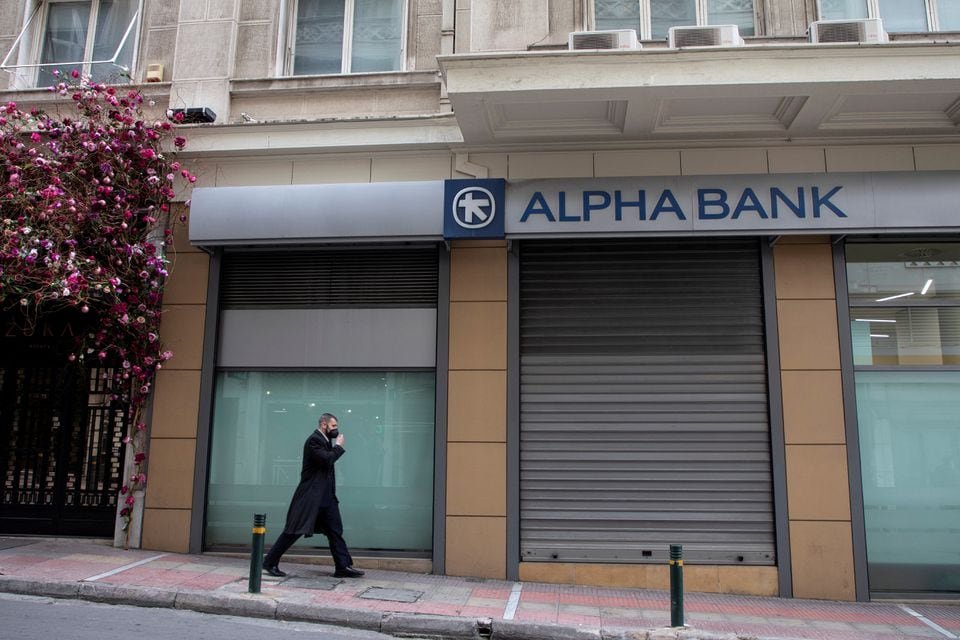 A man walks past an Alpha Bank branch in Athens, Greece, January 17, 2022. REUTERS/Louiza Vradi/File Photo