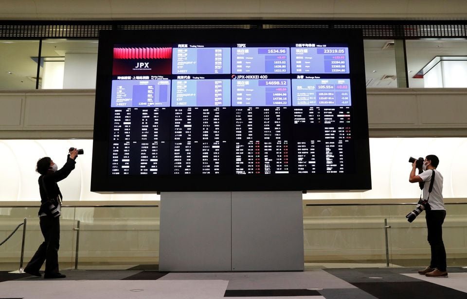 Photographers take photos near a large screen showing stock prices at the Tokyo Stock Exchange (TSE) after market opens in Tokyo, Japan October 2, 2020. REUTERS/Kim Kyung-Hoon/File Photo
