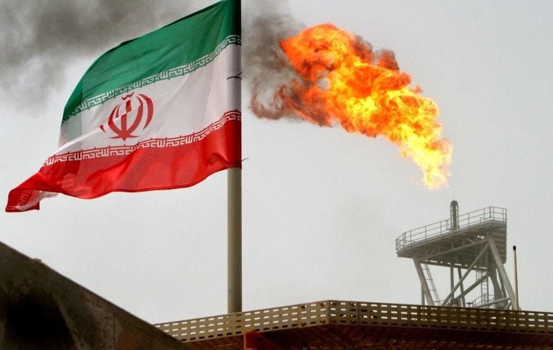 A gas flare on an oil production platform is seen alongside an Iranian flag in the Gulf July 25, 2005. REUTERS/Raheb Homavandi