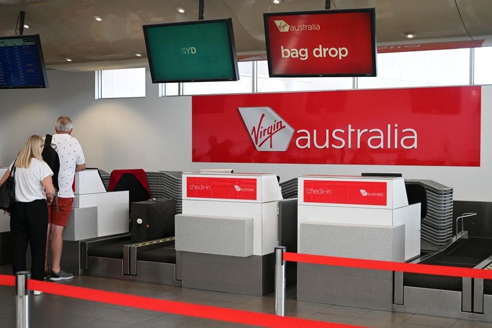 Travelers stand at a Virgin Australia Airlines counter at Kingsford Smith International Airport, in Sydney, Australia, March 18, 2020. REUTERS/Loren Elliott