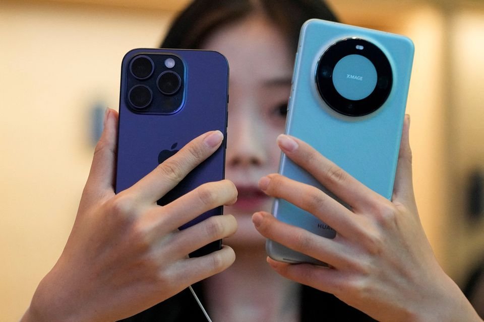 A woman looks at a new iPhone 15 Pro and a Huawei Mate 60 Pro as Apple's new iPhone 15 officially goes on sale across China, at an Apple store in Shanghai, China September 22, 2023. REUTERS/Aly Song/File Photo