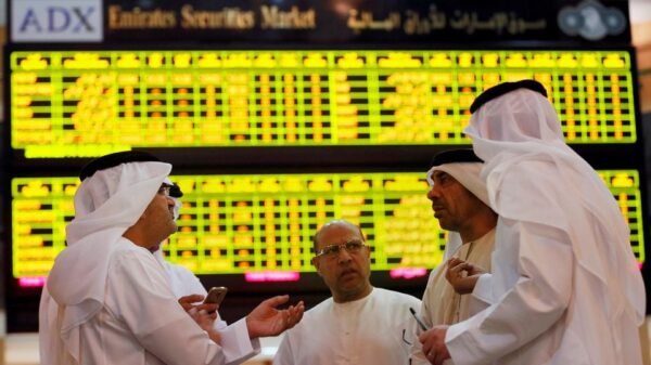 Investors speak in front of a screen displaying stock information at the Abu Dhabi Securities Exchange, United Arab Emirates June 25, 2014. REUTERS/Stringer/File Photo