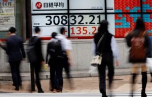 Pedestrians walk past an electronic board displaying Nikkei share average, outside a brokerage in Tokyo, Japan, October 31, 2023. REUTERS/Kim Kyung-Hoon/File Photo