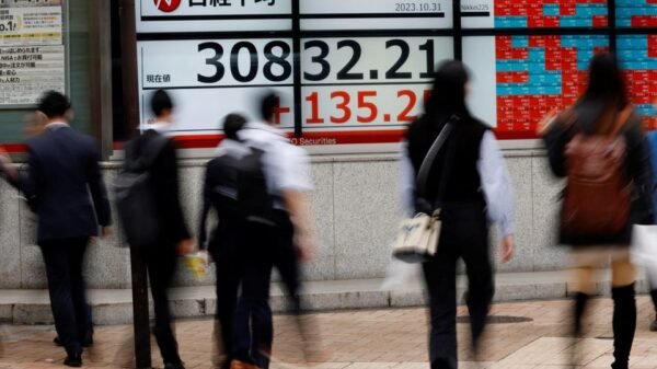 Pedestrians walk past an electronic board displaying Nikkei share average, outside a brokerage in Tokyo, Japan, October 31, 2023. REUTERS/Kim Kyung-Hoon/File Photo
